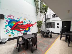 a restaurant with tables and a wall with a mural at Rock Hostel Medellin in Medellín
