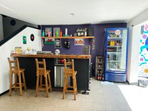 a bar in a room with two stools and a refrigerator at Rock Hostel Medellin in Medellín