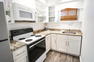 a white kitchen with a stove and a microwave at Drop Anchor Resort & Marina in Islamorada