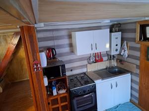 uma pequena cozinha com fogão e armários brancos em Cabaña Alba em Puerto Montt