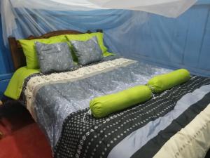 a bed with two green pillows on top of it at Farm Lodge La Cabaña 