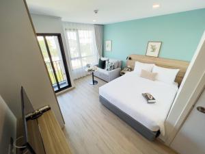 1 dormitorio con 1 cama blanca grande y 1 silla en Wellness Stay & Hotel Sukhumvit 107, en Bangna