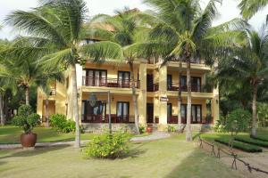 a yellow building with palm trees in front of it at Pandanus Resort in Mui Ne