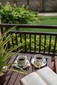 two cups of coffee and an open book on a wooden table at Pandanus Resort in Mui Ne