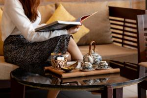 a woman reading a book while sitting on a couch at Pandanus Resort in Mui Ne