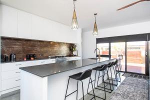 a kitchen with white cabinets and a counter with bar stools at Bayside Luxury Escape Busselton with WiFi in Busselton