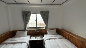 two beds in a room with a window at 雲台客棧民宿 in Nangan