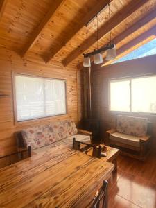 uma sala de estar com uma mesa de madeira e um sofá em Cabañas Lihuén SPA em Parral