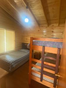a bedroom with a bunk bed in a log cabin at Cabañas Lihuén SPA in Parral