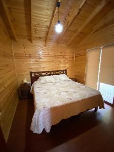 um quarto com uma cama num chalé de madeira em Cabañas Lihuén SPA em Parral