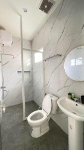 a bathroom with a white toilet and a sink at The Glory Villas in Batu