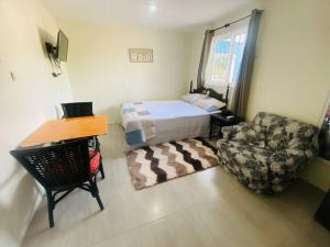 1 dormitorio con cama, silla y escritorio en Mona Cottage en Kingston