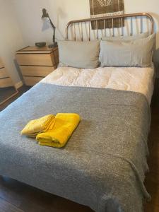 una coperta gialla seduta sopra un letto di Spacious 1-bed flat in North Kensington a Londra