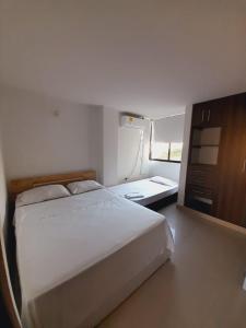 1 dormitorio con 1 cama blanca grande y escritorio en Apartamento Rodadero, en Santa Marta