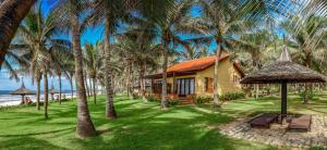 a house on the beach with palm trees at Pandanus Resort in Mui Ne