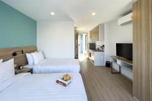 Wellness Stay & Hotel Sukhumvit 107 في بانغنا: غرفه فندقيه سريرين وتلفزيون