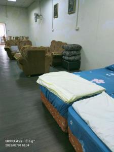 Habitación con 2 camas, sofás y sillas. en KERAYONG IMPIAN HOMESTAY, en Kampong Kerayong