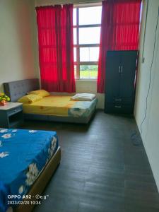 1 dormitorio con 2 camas y una ventana con cortinas rojas en KERAYONG IMPIAN HOMESTAY, en Kampong Kerayong