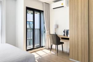 a bedroom with a bed and a desk and a window at Wellness Stay & Hotel Sukhumvit 107 in Bangna
