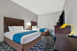a hotel room with two beds and a flat screen tv at Studio 6-Pleasanton, TX in Pleasanton