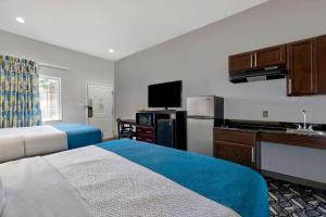 a room with two beds and a kitchen with a refrigerator at Studio 6-Pleasanton, TX in Pleasanton