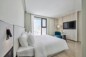 ein Hotelzimmer mit einem weißen Bett und einem TV in der Unterkunft December Hotel in Nha Trang