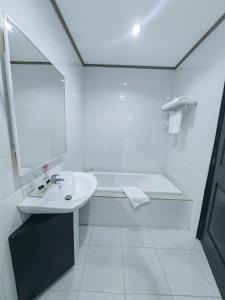 a white bathroom with a sink and a bath tub at Batangas Country Club in Batangas City