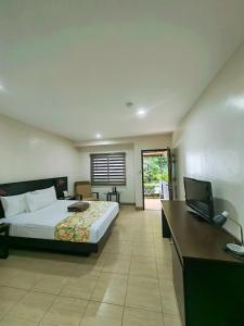 a bedroom with a bed and a desk with a laptop at Batangas Country Club in Batangas City