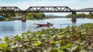 a boat in the water under a bridge at Felix River Kwai Resort - SHA Plus,Certified in Kanchanaburi City