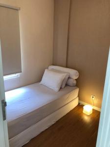 a small room with a white bed with a light at Madison Park Apartment 2 Bedroom near Central Park Mall in Jakarta