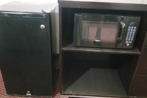 a black microwave oven sitting in a cabinet at OSU 2 Queen Beds Hotel Room 131 Wi-Fi Hot Tub Booking in Stillwater