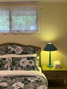 a bedroom with a bed and a window with a lamp at English Gardens - Forest Spa Suite in Springbrook