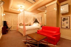 1 dormitorio con 1 cama y 1 silla roja en HOTEL555 伊豆長岡, en Izunokuni