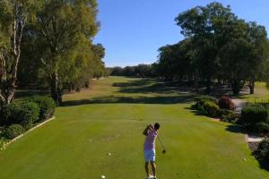 a woman is playing golf on a green at 13 Cypress Lane in Woorim