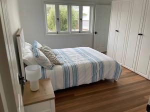 um quarto com uma cama com um cobertor listrado e uma janela em 13 Cypress Lane em Woorim