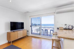 a living room with a television and a balcony at Cottesloe Azura Apartment in Perth