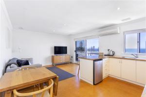 a kitchen and living room with a table and a kitchen and a couch at Cottesloe Azura Apartment in Perth