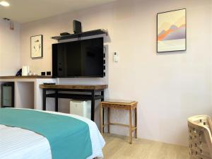 a bedroom with a bed and a flat screen tv at 95 Pavilion in Jiufen