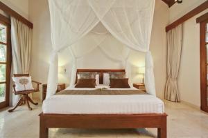 1 dormitorio con cama con dosel y cortinas en Villa Alu Lima, en Seminyak