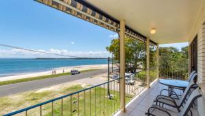 een balkon met een tafel en stoelen en uitzicht op het strand bij Water Views - Top Floor -Clearview Apartments South Esp, Bongaree in Bongaree