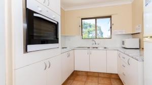 a kitchen with white cabinets and a sink and a window at Fantastic Views From Top Floor in Bongaree