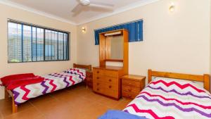 a bedroom with two beds and a dresser and a mirror at Fantastic Views From Top Floor in Bongaree