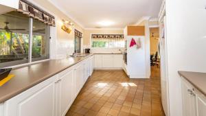 a kitchen with white cabinets and a tile floor at Bribie Beach House, Waterfront directly across the road - Solander Esp, Banksia Beach in Old Bribie