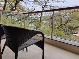 a wicker chair sitting on a balcony looking out a window at Tara Suites Premium rooms in Central Indiranagar in Bangalore