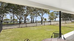 a patio with a fence and a field of grass at Ground floor air conditioned, fabulous waterviews overlooking Pumicestone Passage in Bongaree