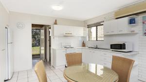 a kitchen with white cabinets and a table and chairs at Ground floor air conditioned, fabulous waterviews overlooking Pumicestone Passage in Bongaree