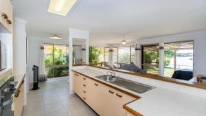 a kitchen with a sink and a living room at Lowset home on the canal - Dolphin Dr, Bongaree in Bongaree
