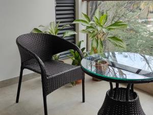 uma cadeira de vime e uma mesa de vidro na varanda em Tara Suites Premium rooms in Central Indiranagar em Bangalore
