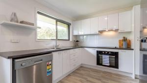 a kitchen with white cabinets and a stainless steel dishwasher at Freshly revovated Dog Friendly House walking distance to Waterfront! in Bellara