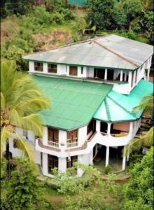 a large white house with a green roof at V6 Holiday Bungalow in Badulla